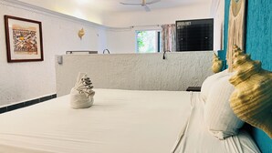 Habitación de hotel con una cama bien hecha, un ventilador de techo, una ventana con cortinas y un aire acondicionado de pared.