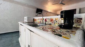Una cocina con salpicadero de azulejos, microondas, fregadero y cafetera.