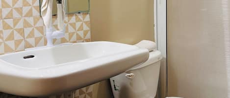 Un baño con un lavamanos blanco, un inodoro y una cortina de ducha.