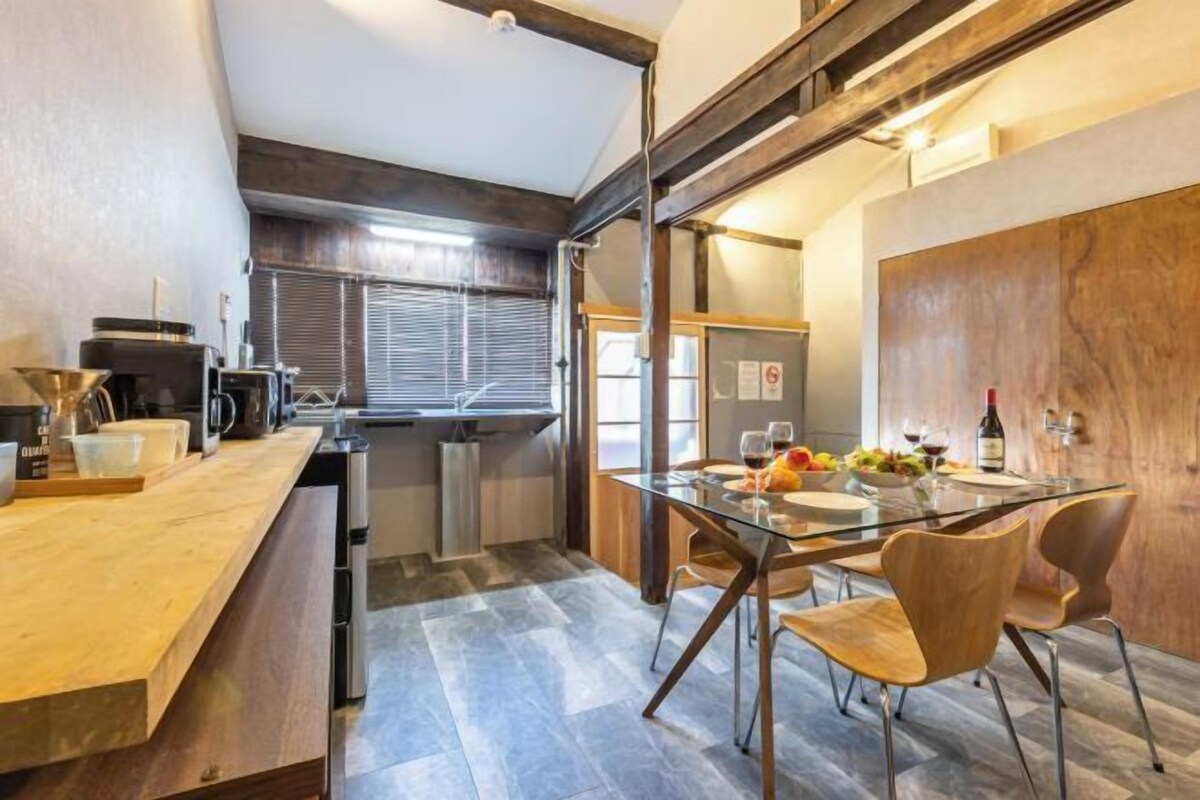 A modern kitchen with a glass dining table, wooden chairs, and a built-in oven.