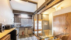 A compact kitchen with modern appliances, a glass dining table, and wooden chairs. - Rent Tsuruhashi (Osaka)