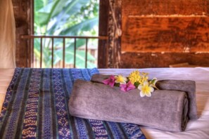 A bed with a blue patterned bedspread, a rolled towel, and a flower arrangement. - Villas Samalama Gili Trawangan (Gili Trawangan)
