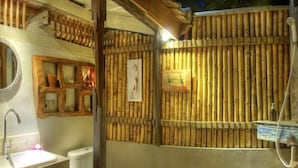Um banheiro com parede de bambu, pia e vaso sanitário.