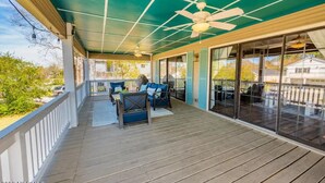 A covered outdoor deck with wooden flooring, a ceiling fan, and a seating area with a table and chairs. - Beach Daze Duplex! Natural Light! Fenced Yard! Dogs Welcome! 5 blocks to beach!  (Carolina Beach)