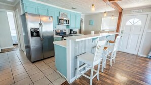 A kitchen with teal cabinets, a stainless steel refrigerator, a built-in oven, and a bar area with white chairs. - Beach Daze Duplex! Natural Light! Fenced Yard! Dogs Welcome! 5 blocks to beach!  (Carolina Beach)