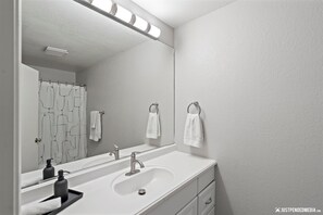 A bathroom with a large mirror, a white sink, a faucet, and a towel rack. - Westchester Lagoon Getaway (Anchorage)