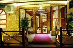 L’entrée d’un hôtel, avec un tapis rouge, une arche en bois et un escalier menant à l’entrée.