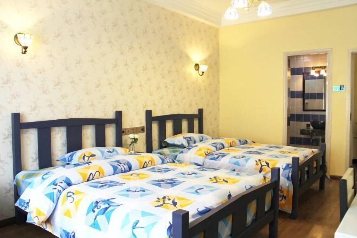 A room with two beds, wooden headboards, and a bathroom visible through an open door.