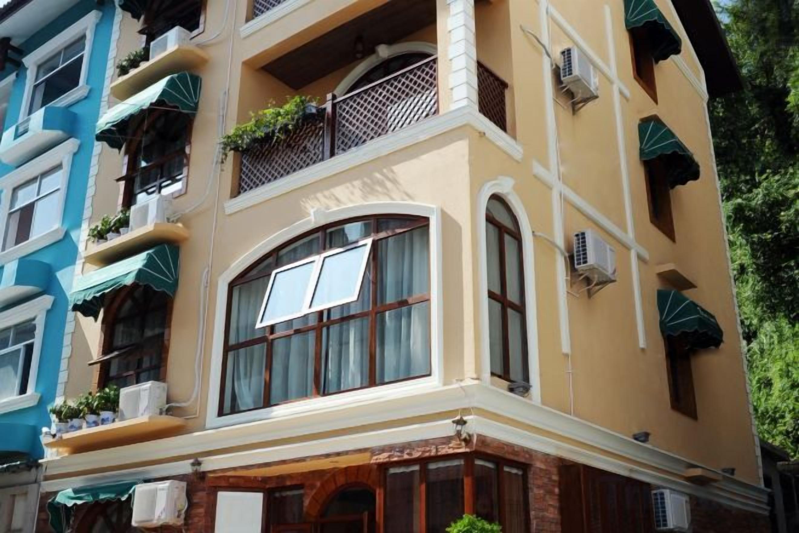 A multi-story building with balconies, air conditioning units, and a corner entrance.
