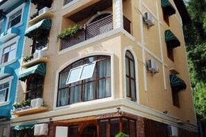 Un immeuble à plusieurs étages doté de balcons, de climatiseurs et d’une entrée située à l’angle.