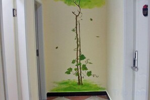 A hallway with a door on the right and a wall with a mural of a tree. - Laimi Theme Inn (Zhangjiajie)