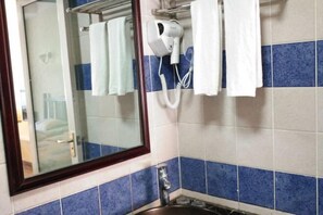 A bathroom with a mirror, a hairdryer, and towels hanging on a rack. - Laimi Theme Inn (Zhangjiajie)