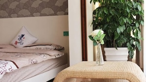 A bed with a patterned bedspread, a pillow with a design, and a bedside table with a vase of flowers. - Laimi Theme Inn (Zhangjiajie)