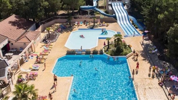 Ein Swimmingpool mit Rutsche, umgeben von Liegestühlen und Sonnenschirmen.