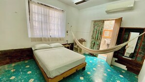 Une chambre à coucher avec un lit, un hamac, une fenêtre avec des rideaux et un sol carrelé.