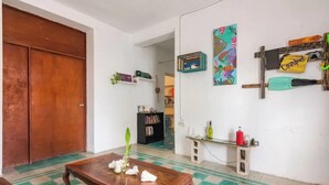 Un salon avec une table en bois, un canapé, une bibliothèque, un tableau et une porte.