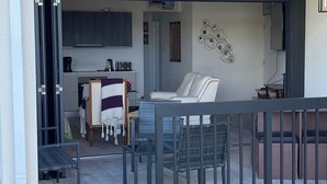 Une cuisine moderne avec des meubles de couleur sombre, une machine à café et un grille-pain. On y trouve également un coin repas avec une chaise blanche et une table.