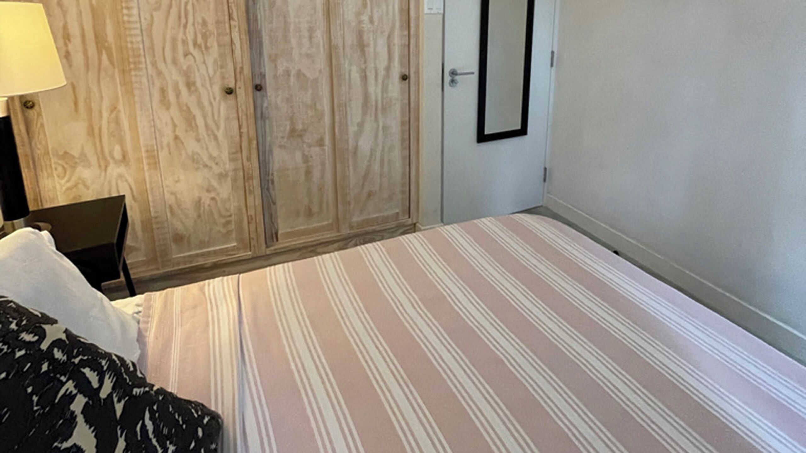 Une chambre d’hôtel avec un lit, une chaise, une armoire et une porte.