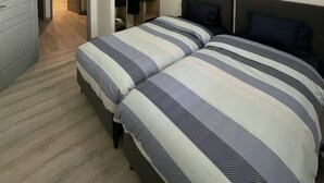 A bedroom with two beds, a closet, and a door leading to another room. - Maison à la Hauteur d un Beau Village (Apt)