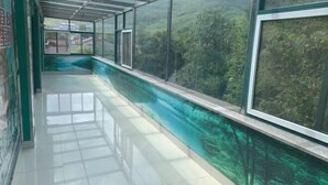 A corridor with glass walls and a view of a forested area. - Liyang Hot Spring Garden Hotel (Liyang)