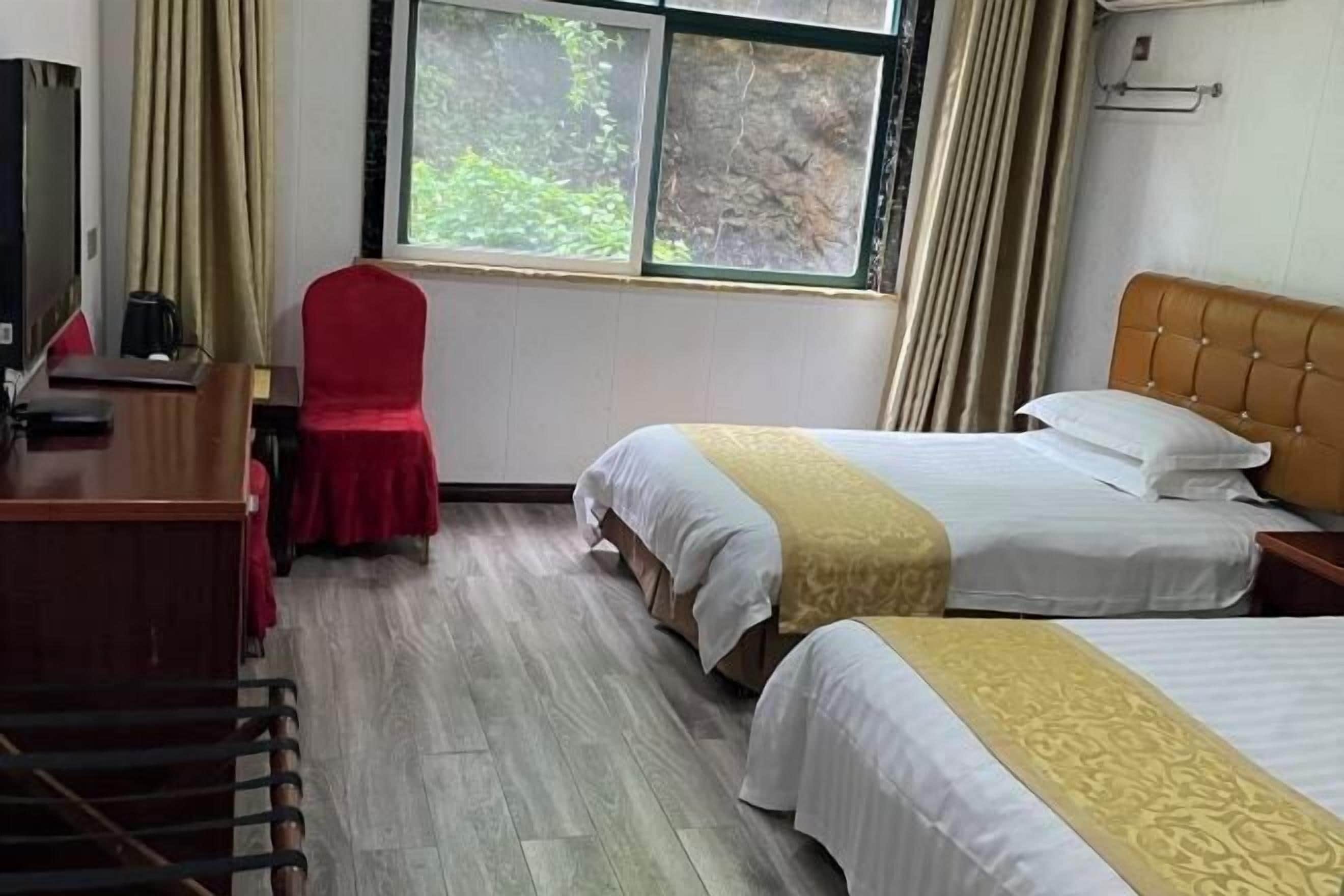 A hotel room with two beds, a desk, a chair, and a window with curtains.