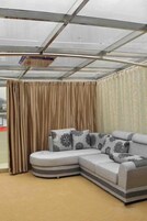 Habitación con un amplio sofá modular, techo de cristal y vistas al exterior.