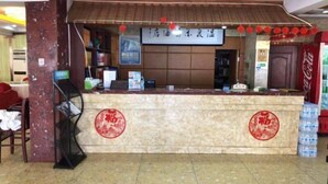 A hotel reception area with a marble counter, red circular decorations, a Coca-Cola refrigerator, and a sign with Chinese characters. - Liyang Hot Spring Garden Hotel (Liyang)