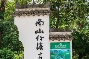 A traditional Chinese-style sign with calligraphy, a tiled roof, and a poster with text and a landscape image.