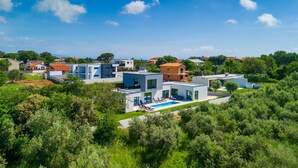 Una zona residencial moderna con casas contemporáneas, una piscina y abundante vegetación.