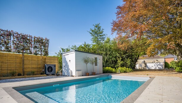 A rectangular swimming pool with a tiled deck surrounding it, a small white shed, and a wooden fence in the background. - 1 bedroom accommodation in Wykenham, near Spalding (Wykenham, near Spalding)