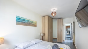 Ein modernes Schlafzimmer mit einem Bett, einem Gemälde, einer Lampe und einem Kleiderschrank.