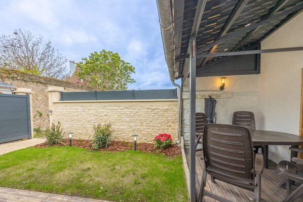 A patio area with a table and chairs, a stone wall, and a garden with plants and flowers.