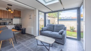 Eine moderne Küche mit einer Dachfensterkuppel, einem grauen Sofa und einem kleinen Tisch.