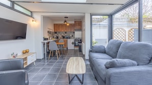Ein moderner Wohnraum mit Küche, Essbereich und einem großen grauen Sofa.