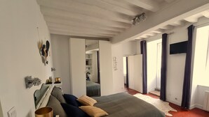 Une chambre à coucher avec un lit, une table de chevet, un miroir et une armoire.