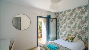Un dormitorio con cama, un espejo redondo, una silla y vistas al exterior.