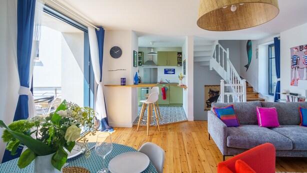 Una sala moderna con un sofá, una mesa de comedor y una zona de cocina al fondo.