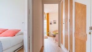 A hotel room with a bed, a wooden door, and a hallway leading to another room. - L'Atypique - Appt à 150m de la plage (Arcachon)