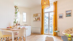 A bright, modern living room with a dining area, a sofa, and a table with a plant. - L'Atypique - Appt à 150m de la plage (Arcachon)