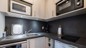 A modern kitchen with a microwave, oven, sink, and dishwasher. - Le Corbier - Studio avec belle vue montagne (Villarembert)