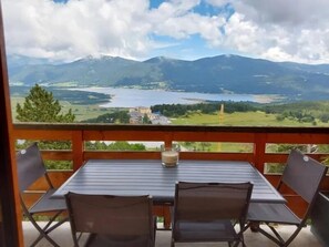 A balcony with a table and chairs overlooking a mountainous landscape and a lake. - Cosy Wood - Appt vue lac et montagne (Les Angles)