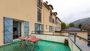 A rooftop terrace with a table and chairs, a view of the surrounding buildings, and a mountain in the background. - Cal Bourquets - Vue montagne (Err)