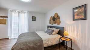 A neatly arranged bedroom with a bed, bedside lamp, and a wall art piece. - Cal Bourquets - Vue montagne (Err)