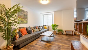 A modern living room with a grey sofa, wooden coffee table, and a large potted plant. - Cal Bourquets - Vue montagne (Err)