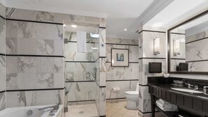 A modern bathroom with marble walls, a walk-in shower, a bathtub, and a vanity with a large mirror. - FontaineBleau Balcony 10 min from SoBe (Miami Beach)