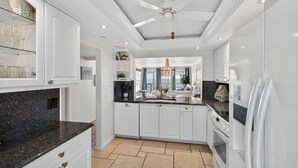 Une cuisine moderne avec des meubles blancs, des plans de travail en granit et un îlot central.