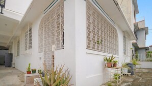 A white building with large windows and a white door. There are potted plants outside.