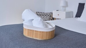 Siististi pedattu sänky, päällä valkoinen peitto ja sängynpäädyssä puinen jalkatuki.