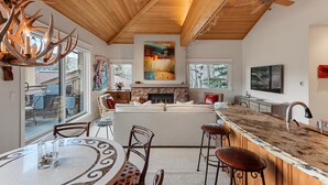 A modern kitchen with a wooden ceiling, a large island with bar stools, and a fireplace. - Gorgeous View, 3 minute shuttle  to ski lifts Renovated- Great Location  (Snowmass Village)