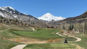 A golf course with a clear path, a golf cart, and a mountain in the background. - Gorgeous View, 3 minute shuttle  to ski lifts Renovated- Great Location  (Snowmass Village)